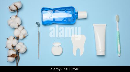 Bain de bouche, tube de dentifrice, fil dentaire et miroir médical sur fond bleu, hygiène buccale Banque D'Images