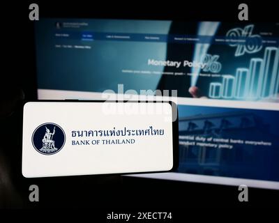 Personne tenant un smartphone avec le logo de l'institution financière thaïlandaise Banque de Thaïlande (BOT) en face du site Web. Concentrez-vous sur l'affichage du téléphone. Banque D'Images