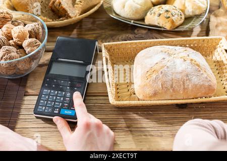 Poinçonner l'argent comptant accepté pour le pain acheté dans la caisse enregistreuse. Boulangerie familiale avec des traditions multi-générations. Banque D'Images