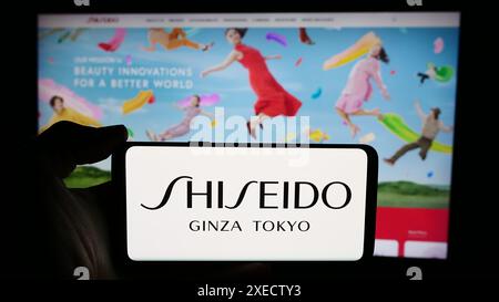 Personne tenant un smartphone avec le logo de la société cosmétique japonaise Shiseido Co. Ltd en face du site Web. Concentrez-vous sur l'affichage du téléphone. Banque D'Images