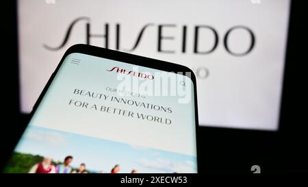 Téléphone portable avec page Web de la société cosmétique japonaise Shiseido Co. Ltd devant le logo de l'entreprise. Concentrez-vous sur le coin supérieur gauche de l'écran du téléphone. Banque D'Images