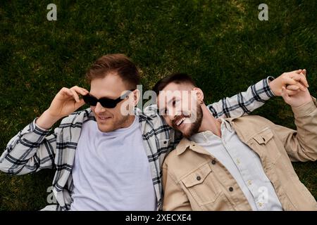 Deux hommes amoureux, allongés sur un champ vert vibrant, appréciant les uns les autres compagnie. Banque D'Images