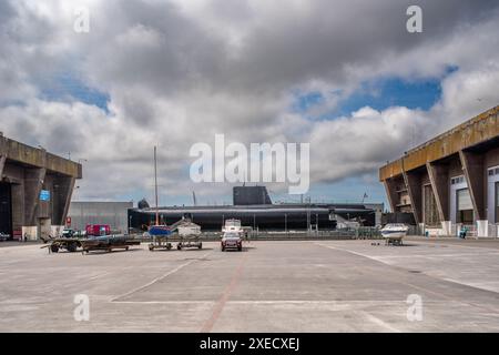 Base de sous-marins allemands de la seconde Guerre mondiale à Lorient, en Bretagne, en France, avec un sous-marin français des années 1960 amarré au milieu de grandes structures en béton. Banque D'Images