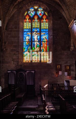 Un vitrail vif représentant une scène religieuse dans l'historique Collegiale Saint Aubin à Guérande, France. Illumine l'intérieur gothique w Banque D'Images