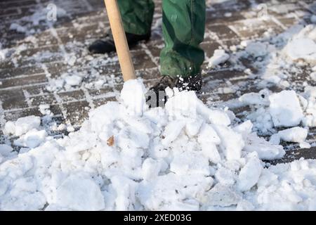Un travailleur manuel ramasse la neige et la glace humides sur un pelle Banque D'Images