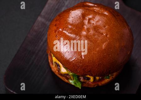 Hamburger avec escalope de bœuf juteuse, fromage, tomates, sel, épices et herbes Banque D'Images