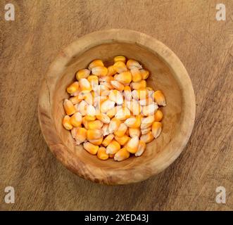 Graines de maïs dans un bol en bois sur une table en bois, vue de dessus. Banque D'Images