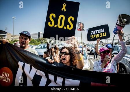 Les familles d'otages et leurs partisans chantent et brandissent des pancartes lisant Ò S.O.só et en hébreu ÒDeal NowÓ alors qu'ils bloquent la voie ferrée Ayalon à tel Aviv, jeudi 27 2024 juin. Les organisations de protestation antigouvernementales ont lancé jeudi une journée de manifestations dans tout le pays, bloquant les principales autoroutes et appelant Israël à faire avancer un accord pour libérer les otages détenus par le Hamas à Gaza, pour mettre fin à la guerre et pour l'éviction du premier ministre Benjamin Netanyahu et des élections anticipées. Photo par Eyal Warshavsky. Banque D'Images