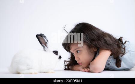 Une petite fille embrasse son lapin moelleux bien-aimé, la beauté de l'amitié entre les humains et les animaux Banque D'Images