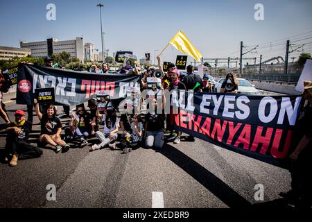 Tel Aviv, Israël. 27 juin 2024. Des familles d'otages et des partisans bloquent l'autoroute Ayalon à tel Aviv. Les organisations de protestation antigouvernementales ont lancé jeudi une journée de manifestations dans tout le pays, bloquant les principales autoroutes et appelant Israël à faire avancer un accord pour libérer les otages détenus par le Hamas à Gaza, pour mettre fin à la guerre et pour l'éviction du premier ministre Benjamin Netanyahu et des élections anticipées. (Photo par Eyal Warshavsky/SOPA images/SIPA USA) crédit : SIPA USA/Alamy Live News Banque D'Images