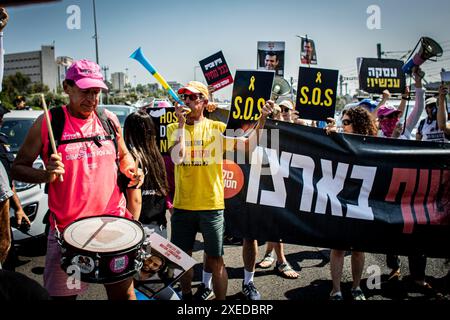 Tel Aviv, Israël. 27 juin 2024. Les familles d'otages et leurs partisans scandent et brandissent des panneaux indiquant « S.O.S » et en hébreu « Deal Now » alors qu'ils bloquent l'autoroute Ayalon à tel Aviv. Les organisations de protestation antigouvernementales ont lancé jeudi une journée de manifestations dans tout le pays, bloquant les principales autoroutes et appelant Israël à faire avancer un accord pour libérer les otages détenus par le Hamas à Gaza, pour mettre fin à la guerre et pour l'éviction du premier ministre Benjamin Netanyahu et des élections anticipées. (Photo par Eyal Warshavsky/SOPA images/SIPA USA) crédit : SIPA USA/Alamy Live News Banque D'Images