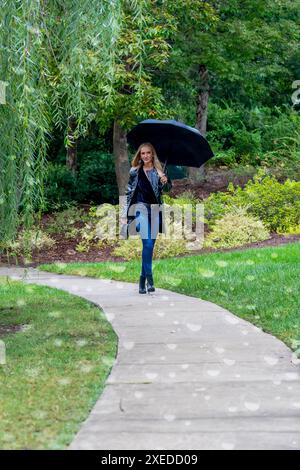 Glimmers in the Gloom : a Woman's graceful Dance with the Rain Banque D'Images