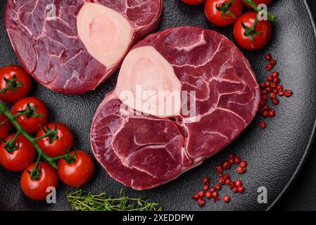 Steak de bœuf cru frais avec os ou ossobuco avec sel, épices et herbes Banque D'Images