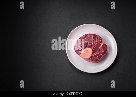 Steak de bœuf cru frais avec os ou ossobuco avec sel, épices et herbes Banque D'Images