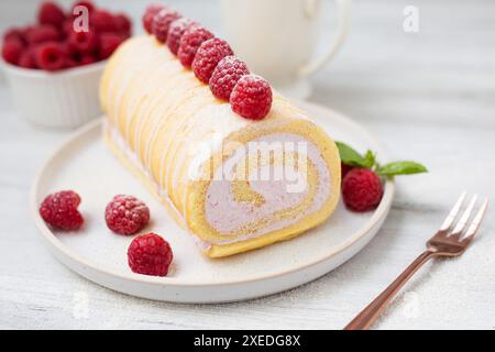 Savoureux petit gâteau, rouleau éponge, rouleau suisse farci avec du fromage à la crème, décoré avec des framboises fraîches. Gâteau fait maison. Banque D'Images