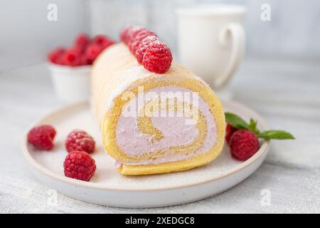 Savoureux petit gâteau, rouleau éponge, rouleau suisse farci avec du fromage à la crème, décoré avec des framboises fraîches. Gâteau fait maison. Banque D'Images