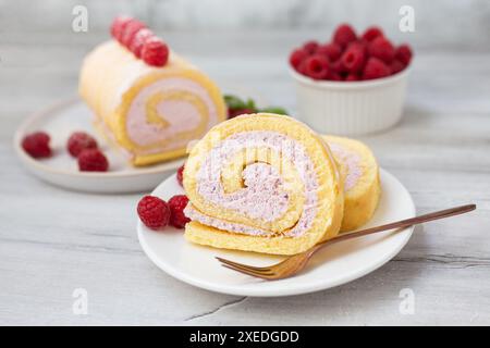 Savoureux petit gâteau, rouleau éponge, rouleau suisse farci avec du fromage à la crème, décoré avec des framboises fraîches. Gâteau fait maison. Banque D'Images