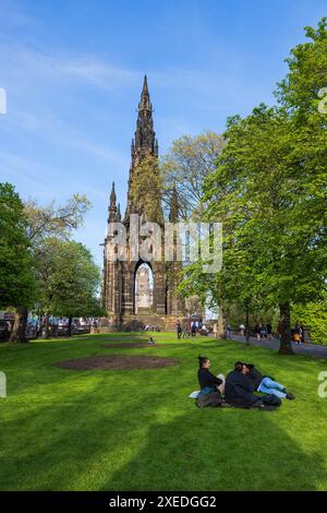 Scott Monument dans la ville d'Édimbourg en Écosse, Royaume-Uni. Monument gothique victorien et les gens se détendent sur la pelouse dans East Princes Street Gardens au printemps. Banque D'Images