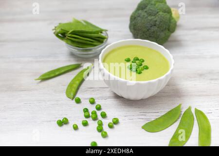 Soupe à la crème avec des petits pois verts sur une table en bois blanc. Aliments sains et diététiques. Nourriture végétarienne. Repas diététique. Banque D'Images