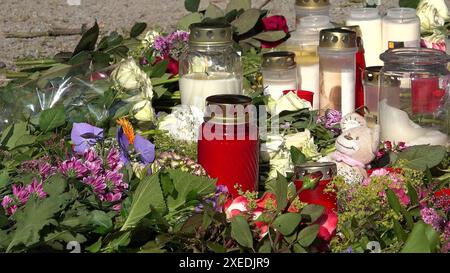 Bad Oeynhausen, Allemagne. 26 juin 2024. Les fleurs gisent et les bougies se tiennent sur le trottoir alors que les gens pleurent après une attaque fatale dans les jardins du spa. Après l'attaque fatale dans les jardins thermaux de Bad Oeynhausen, la police a arrêté un suspect de 18 ans. Un homme de 20 ans a subi des blessures extrêmement graves lors de l'attaque et est mort à l'hôpital peu de temps après. Une escouade des homicides enquête sur l'affaire pour homicide involontaire coupable et lésions corporelles graves. Crédit : Sandra Knauthe/TNN/dpa/Alamy Live News Banque D'Images