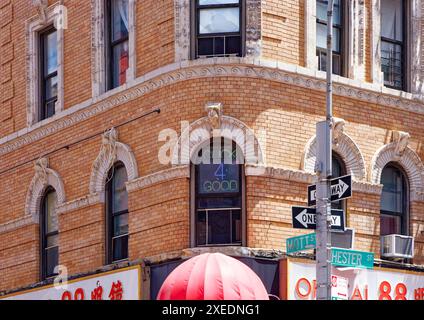 NYC Chinatown : 116 Mott Street, un immeuble de six étages, a un coin arrondi et des détails en terre cuite blanche sur sa façade en briques orange. Banque D'Images