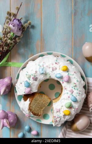 Gâteau de pâques glacé au citron décoré de confiseries et de mini bonbons aux œufs en chocolat sur une table en bois. Banque D'Images