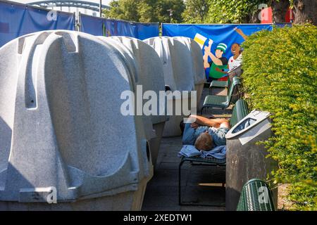 Un homme dort sur un banc placé à côté d'urinoirs mobiles sur la rue Konrad-Adenauer-Ufer dans la zone d'observation publique pendant l'Euro de l'UEFA Banque D'Images