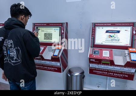 Un homme utilisant la machine électronique sans numéraire de billet de ligne de banlieue de KAI pour acheter, recharger, ou remplir une carte de transport de voyage en train. Jakarta, Indonésie Banque D'Images