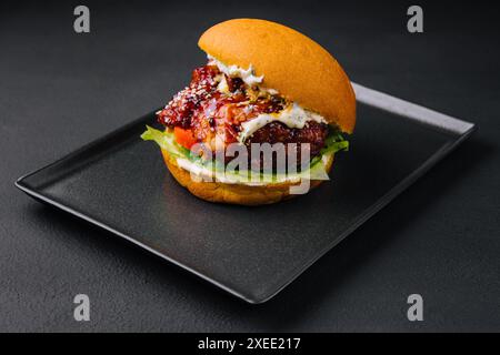 Le burger artisanal est en train de cuire sur un plateau noir Banque D'Images