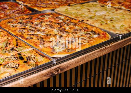 Savoureuses pizzas carrées sur plateaux métalliques Banque D'Images