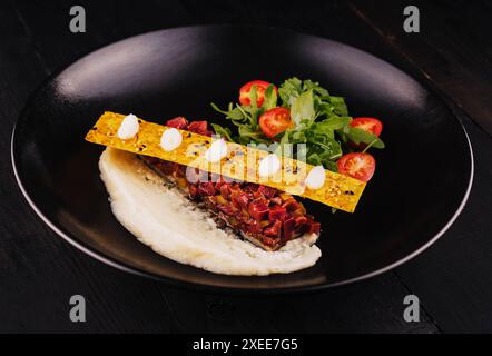 Tartare de steak de bœuf sur assiette noire Banque D'Images