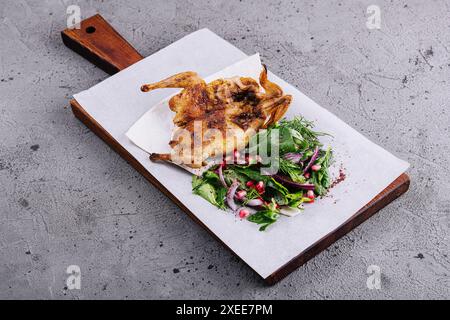 Caille grillée rôtie sur planche à découper en bois avec garniture de salade verte Banque D'Images