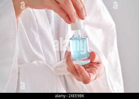 Sérum bleu avec pipette dans une femme mains dans une robe. Banque D'Images