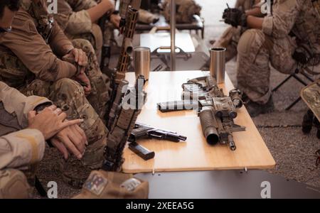 Un groupe de soldats en uniforme de camouflage tient des armes dans une tente de campagne, planifie et prépare l'entraînement au combat. Banque D'Images