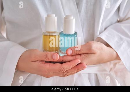 Deux sérums jaunes et bleus dans une femme mains dans une robe. Banque D'Images
