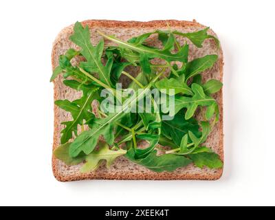 Tranche de pain avec des feuilles de roquette isolées sur blanc Banque D'Images