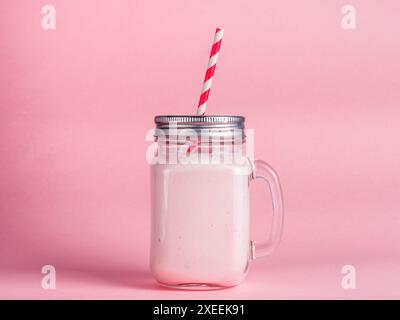 Smoothie à la fraise dans un pot en verre mason sur rose Banque D'Images