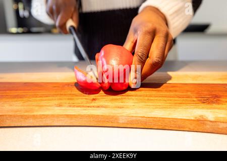 Préparation du poivron rouge frais sur une planche à découper en bois dans la cuisine Banque D'Images