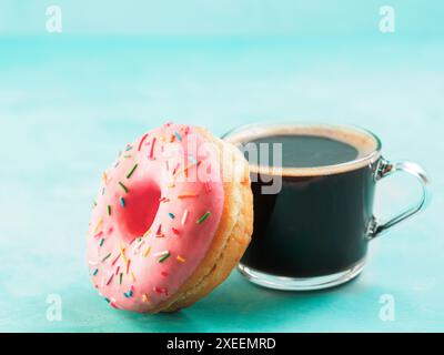 Beignet rose et café sur fond bleu, espace de copie Banque D'Images