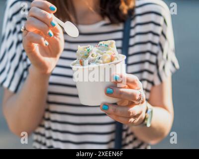 Main tenant la glace roulée dans une tasse à cône Banque D'Images