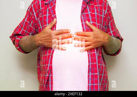 Présentation imitative d'un problème cardiaque ou gastrique d'un homme âgé de plus de soixante ans. Personne âgée ressentant une gêne sur la poitrine ou le haut de l'abdomen. Banque D'Images