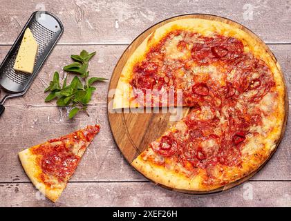 Photographie alimentaire de pizza avec salami épicé ; pepperoni ; piment rouge ; mozzarella ; fromage; porc ; viande ; tomate ; sauce ; frais; origan ; fond ; repas Banque D'Images