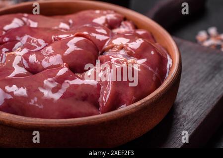 Foie de poulet ou de dinde cru frais dans une assiette en céramique avec sel, épices et herbes Banque D'Images