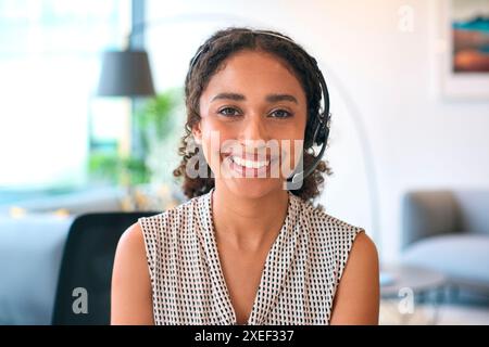 Portrait d'une femme portant un micro-casque assis au bureau travaillant dans le bureau équipe du centre d'appels prenant l'appel Banque D'Images