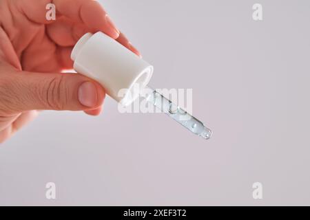 Pipette avec sérum bleu dans une main pour femme. Banque D'Images