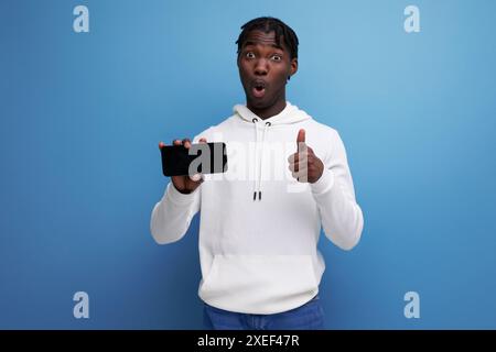 Jeune homme brun à la peau foncée tenant un smartphone avec maquette d'écran Banque D'Images