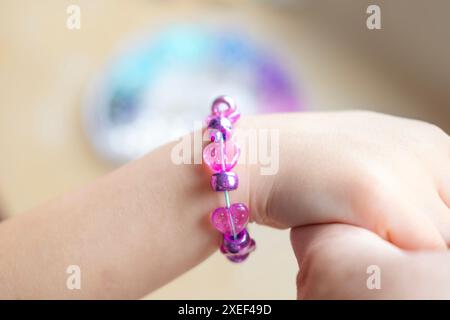 Mains de fille avec bracelet close-up, activités d'art et d'artisanat, projet d'artisanat de bricolage, fabrication de bracelet personnalisé avec des perles colorées, motricité fine Banque D'Images