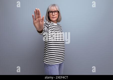 Portrait d'une vieille femme avec les cheveux gris dans une image à la mode sur un fond de studio lumineux Banque D'Images
