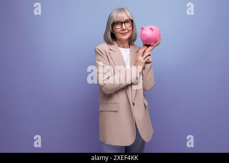 Riche vieille femme avec une tirelire d'argent sur un fond lumineux avec espace de copie Banque D'Images