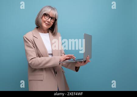 Femme adulte confiante dans une veste avec un ordinateur portable sur un fond lumineux avec espace de copie Banque D'Images